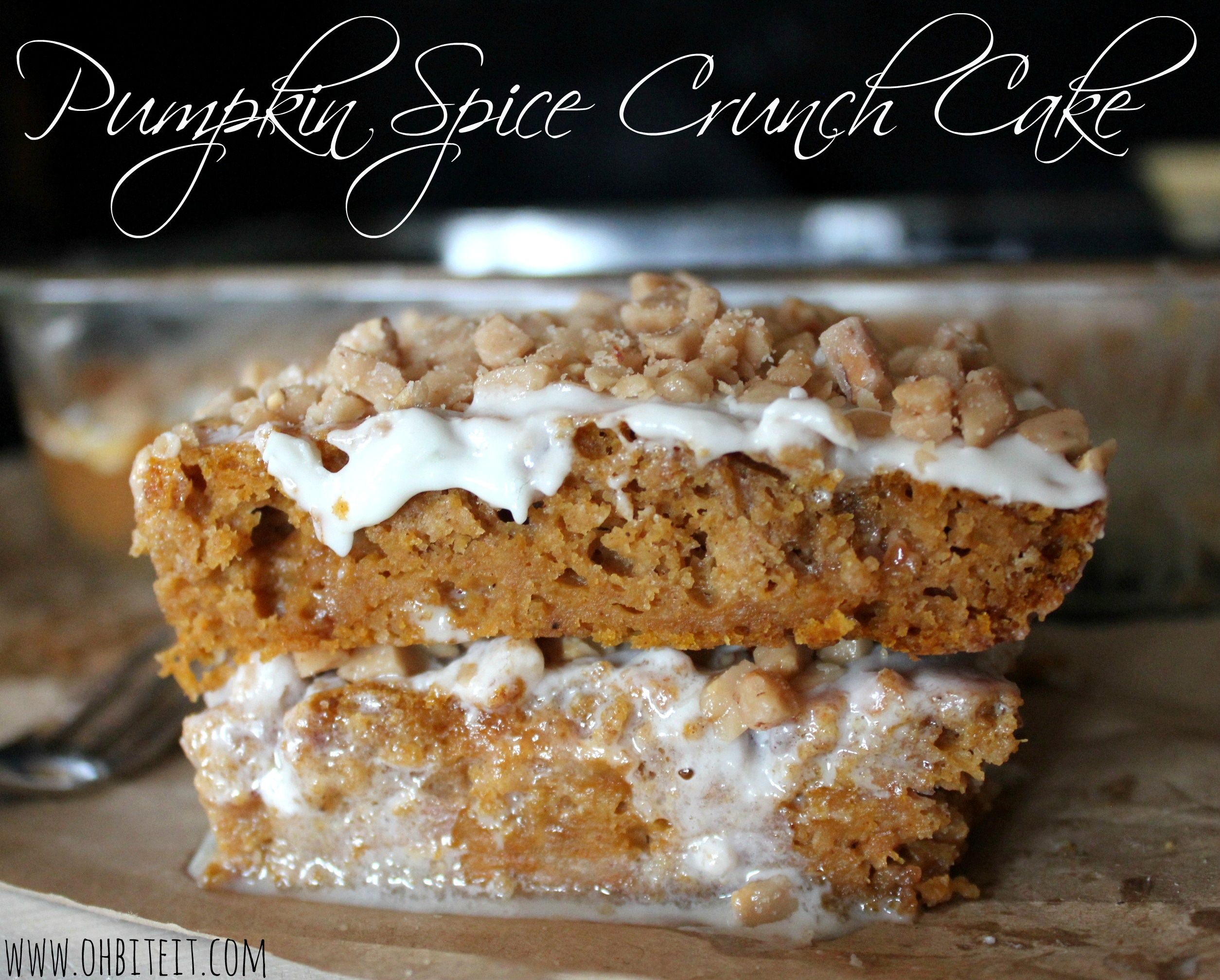 Two slices of pumpkin spice crunch cake sit atop each other with the baking dish visible in the background